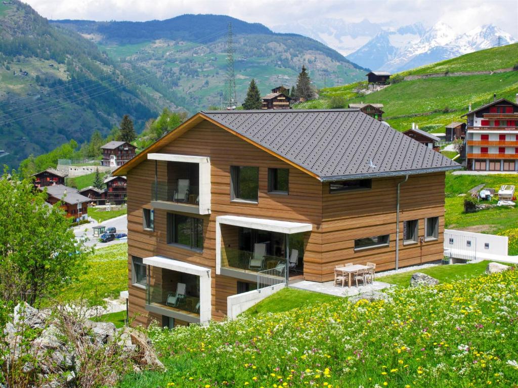 a house on a hill with mountains in the background at Apartment Sera Lodge- Wohnung Brunegghorn by Interhome in Grächen