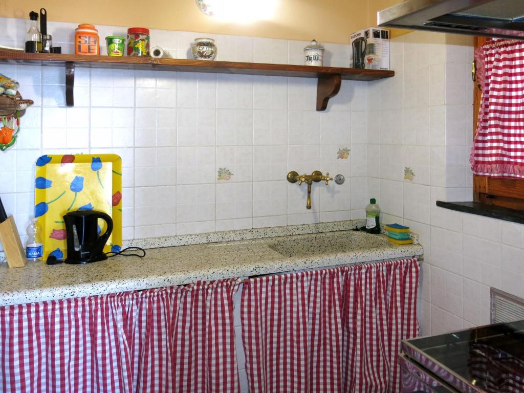 blat kuchenny z czerwono-białą ścianą wyłożoną kafelkami w obiekcie Holiday Home Castagni II - OCT101 by Interhome w mieście Orciatico
