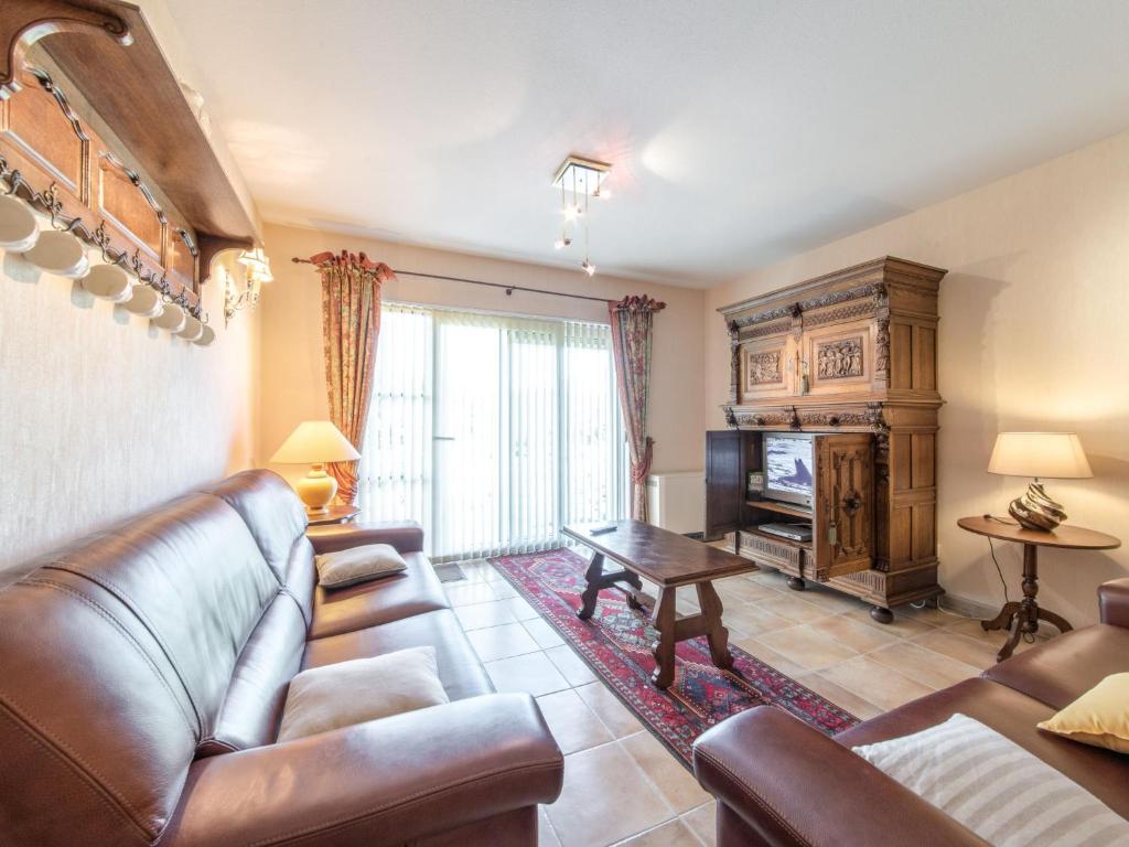 a living room with a leather couch and a television at Apartment Goldsands II 101 with garage by Interhome in De Haan
