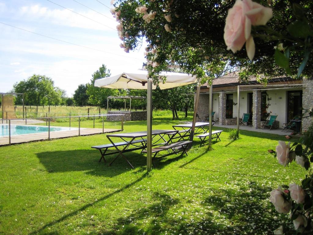 Marmirolo的住宿－科爾特狂歡節農莊酒店，两张野餐桌,放在房子旁边的伞下