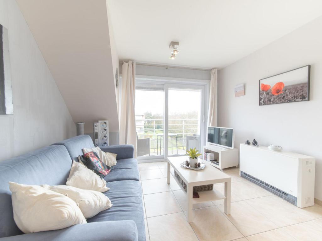 a living room with a blue couch and a tv at Studio Bowie with shared pool by Interhome in De Haan
