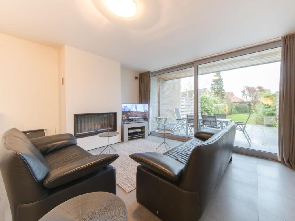 a living room with two chairs and a fireplace at Holiday Home Stella Maris with garage and garden by Interhome in De Haan