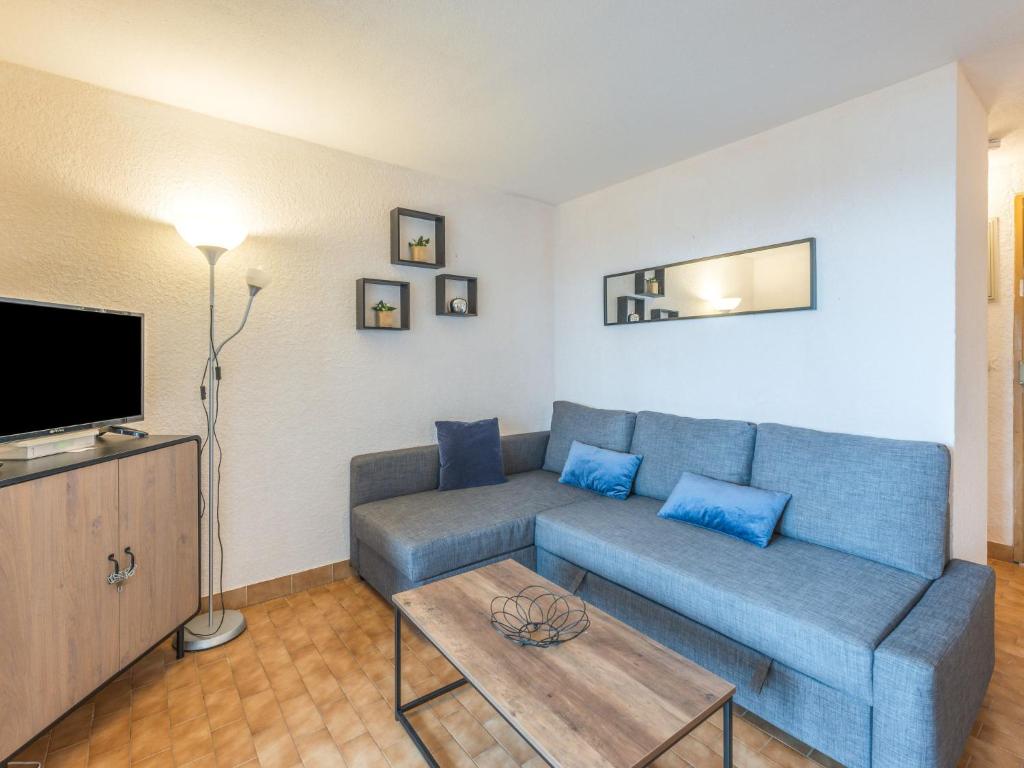 uma sala de estar com um sofá azul e uma mesa em Apartment Les terrasses de la Plage-4 by Interhome em Cap d'Agde
