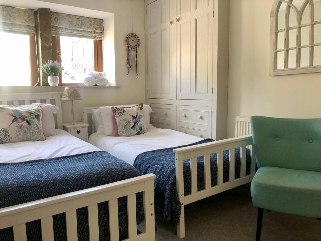 a nursery with two beds and a chair at Wuthering Cottage - Central, Stylish, Cosy, Comfy in Haworth