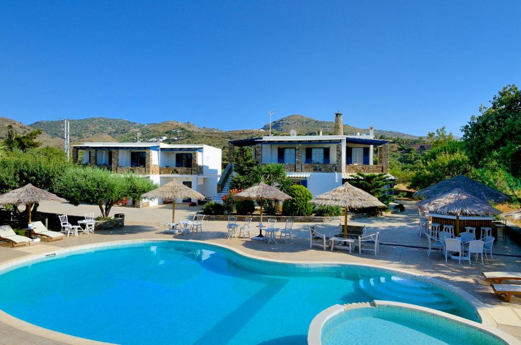 a pool at a resort with chairs and umbrellas at Anemousa Studios in Otziás