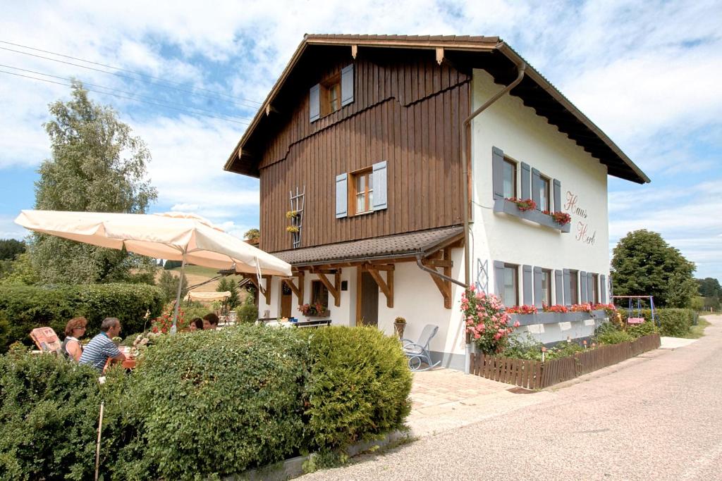 Ein Haus mit Leuten, die davor sitzen. in der Unterkunft Gästehaus Herb in Roßhaupten