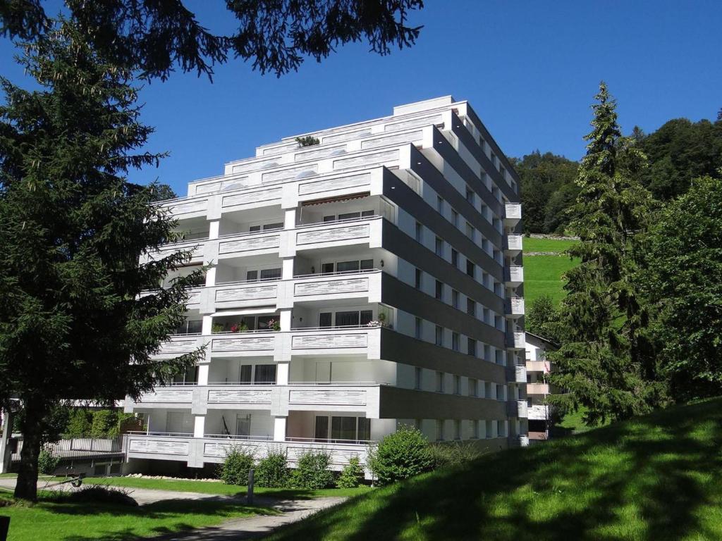 ein weißes Apartmenthaus mit Bäumen davor in der Unterkunft Apartment Sunnmatt 128 by Interhome in Engelberg