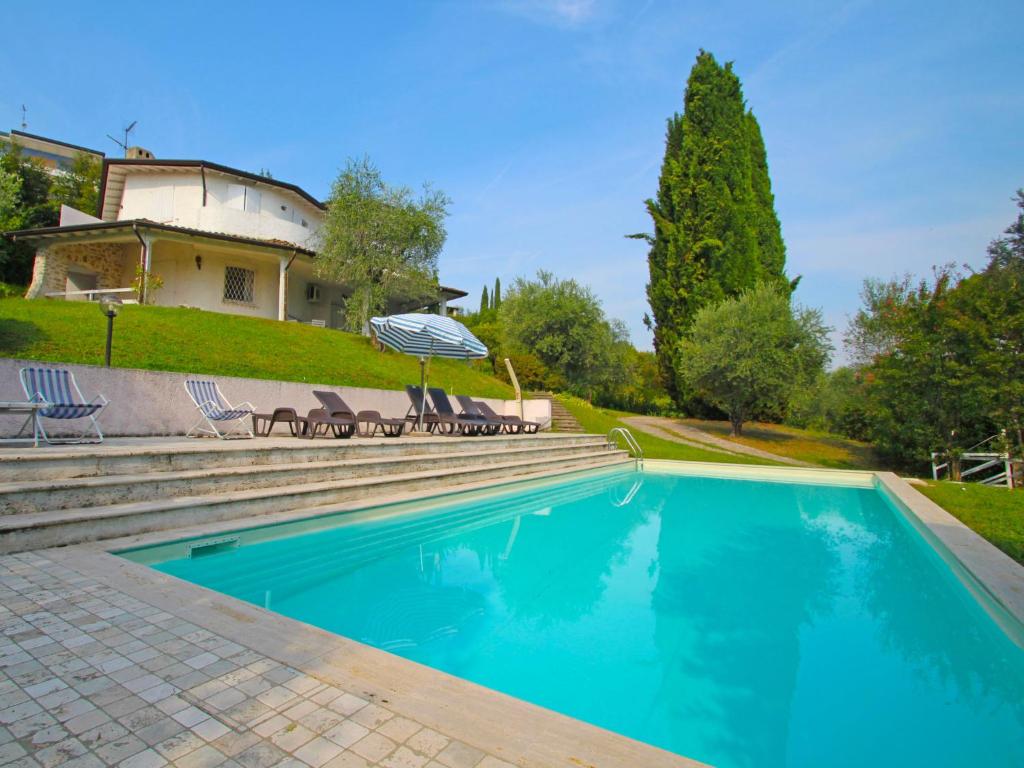 - une piscine avec des chaises et un parasol en face d'une maison dans l'établissement Villa Palomar by Interhome, à San Felice del Benaco