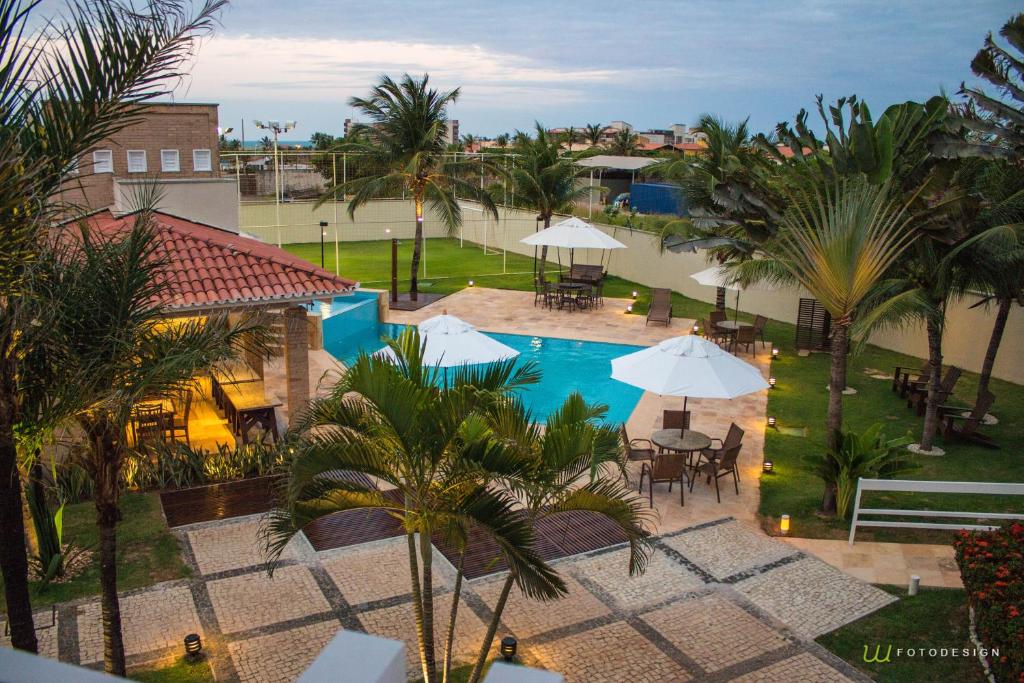 een uitzicht over een zwembad met tafels en parasols bij Pousada Tropical Ilhas in Aquiraz