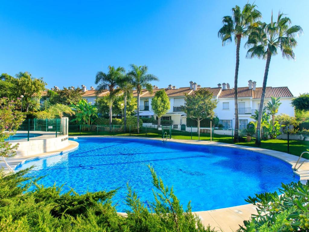 ein großer blauer Pool mit Palmen im Hintergrund in der Unterkunft Holiday Home Olivar by Interhome in Torre de Benagalbón