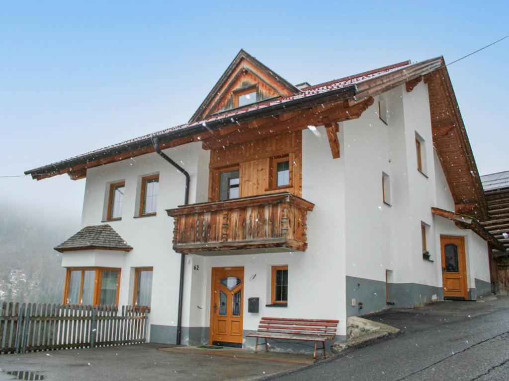 a white building with a wooden balcony and a bench at Apartment Silvretta by Interhome in Kappl