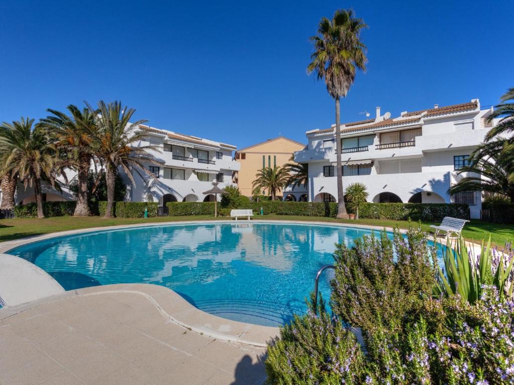 een zwembad met palmbomen en gebouwen bij Apartment Ducados Golf Nat by Interhome in Pals