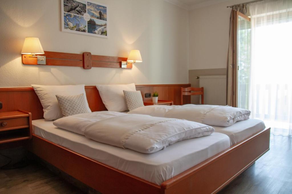 1 cama grande con sábanas blancas y almohadas. en Hotel Bastei, en Altmühldorf