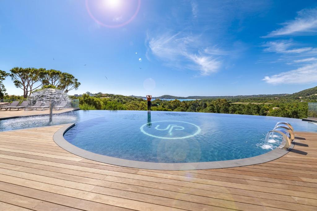 a swimming pool with a wooden deck and a blue sky at U Paesolu in Sainte-Lucie de Porto-Vecchio