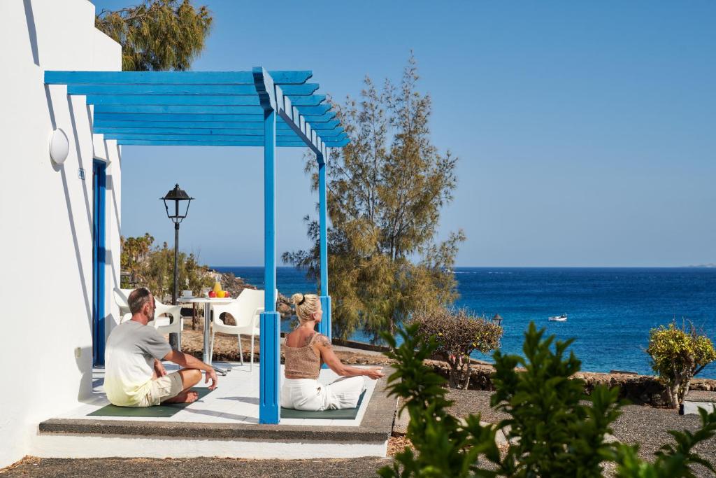 Ein Mann und eine Frau sitzen in einem Pavillon mit Blick auf den Ozean in der Unterkunft Sandos Atlantic Gardens in Playa Blanca