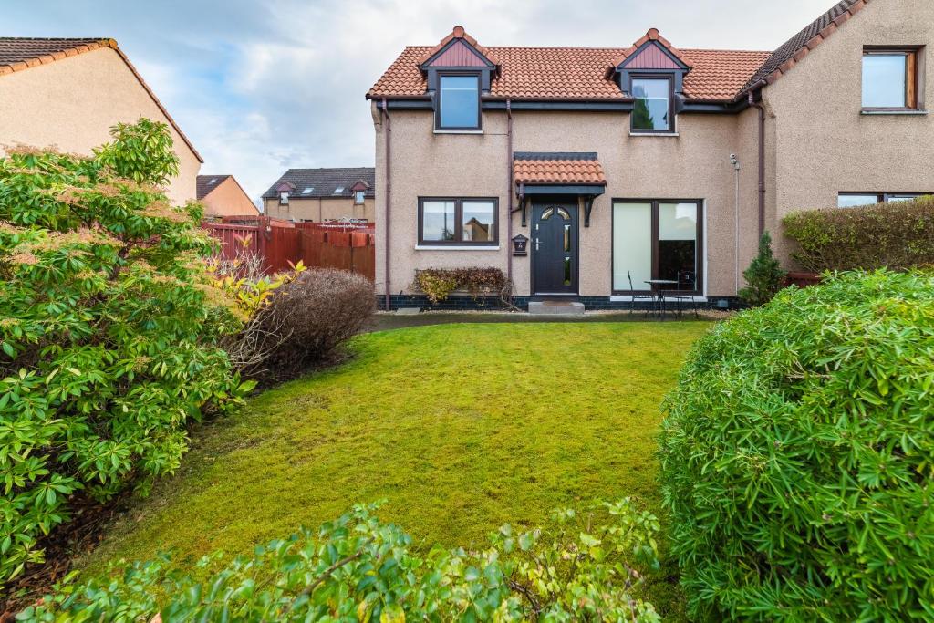 Willa , Cosy house in Inverness في إينفيرنيس: منزل مع ساحة مع ساحة عشبية