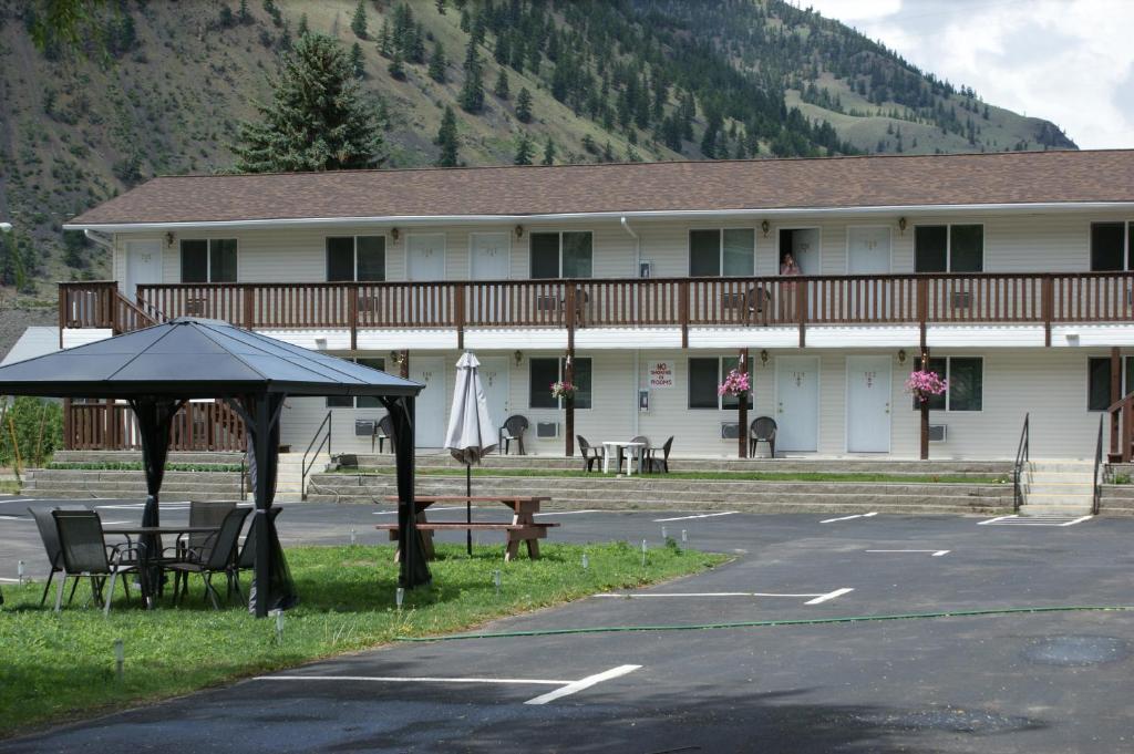 a building with a table and chairs in a parking lot at Elks Motel in Keremeos