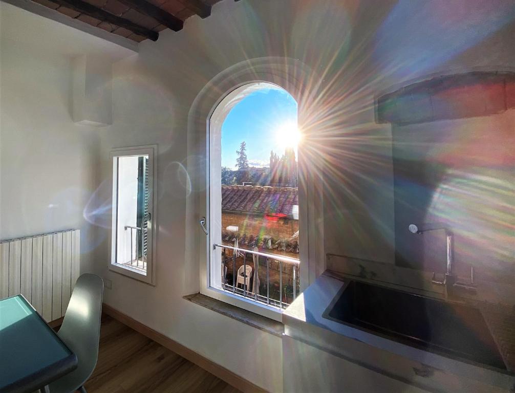 a window in a room with the sun shining through at CASA ILARIA - Luminoso appartamento con vista nel centro storico in Siena
