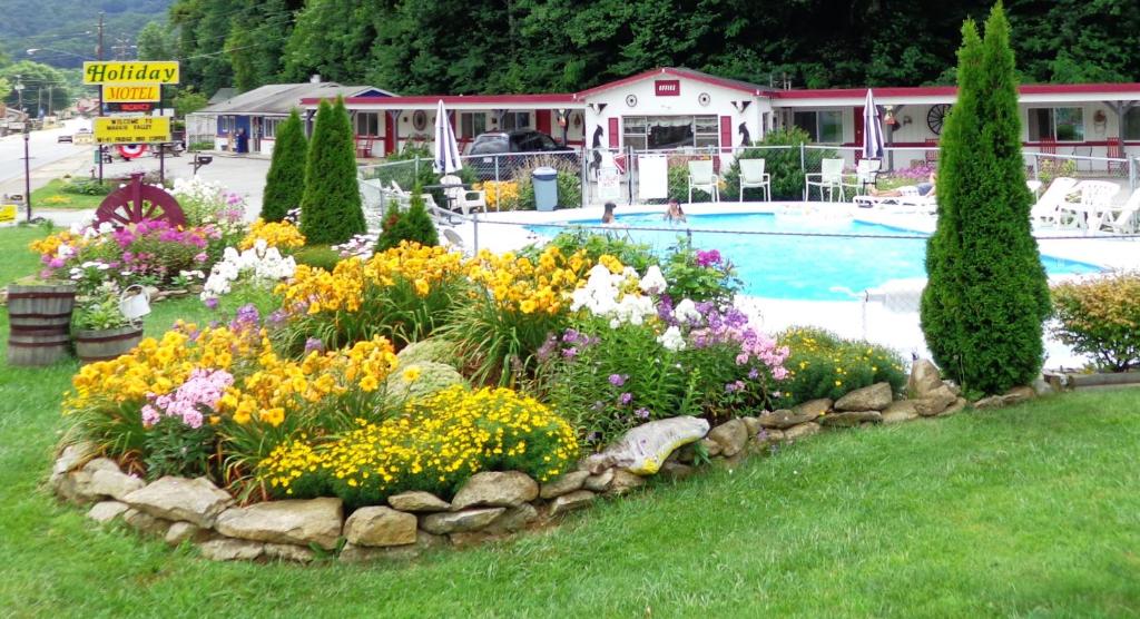 a garden of flowers next to a swimming pool at A Holiday Motel - Maggie Valley in Maggie Valley