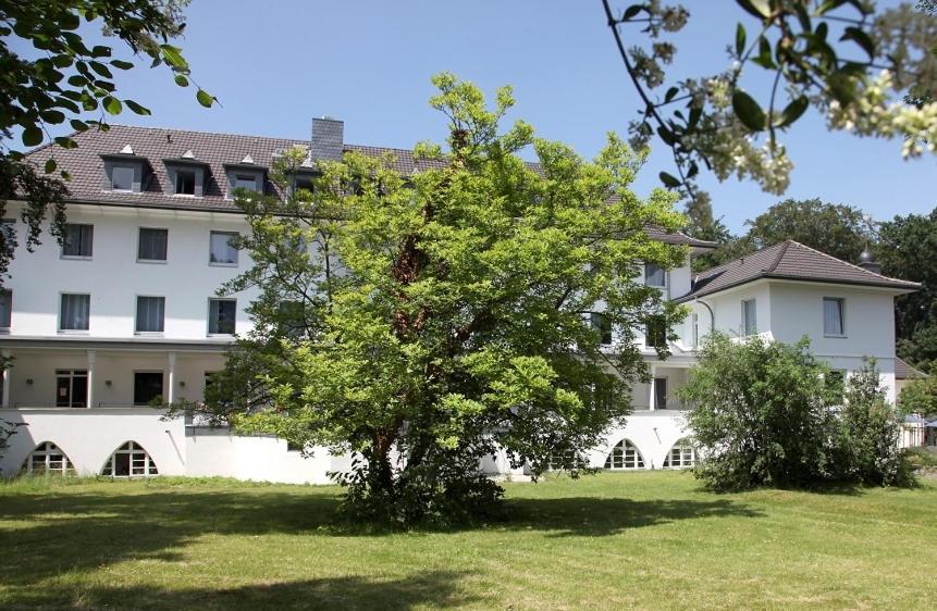 ein großes weißes Gebäude mit einem Baum davor in der Unterkunft Haus Venusberg Jugendbildungsstätte Bonn in Bonn