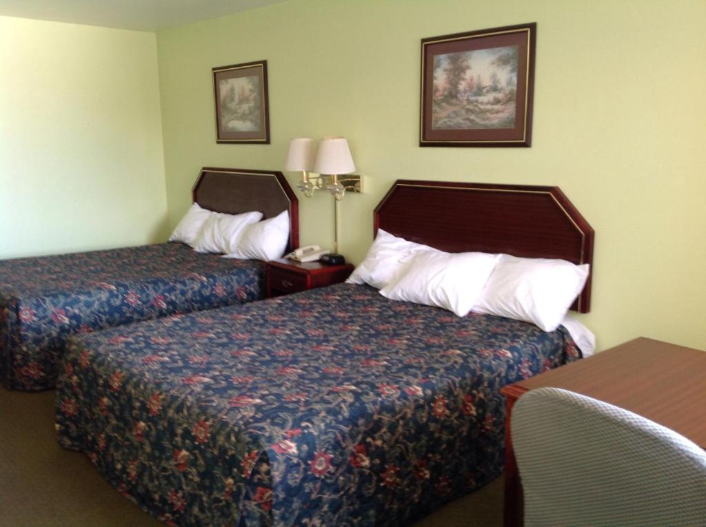 Habitación de hotel con 2 camas y mesa en Executive Inn Tulia en Tulia