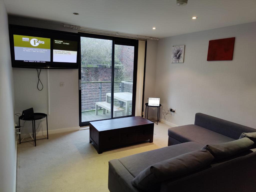 a living room with a couch and a flat screen tv at Cornhill Apartment by Serviced Living Liverpool in Liverpool