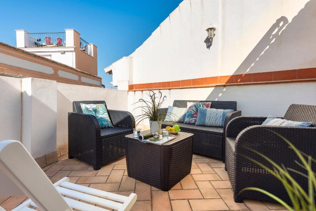 un patio con sillas de mimbre y mesas en un balcón en HSH Suites Santa Catalina, en Sevilla