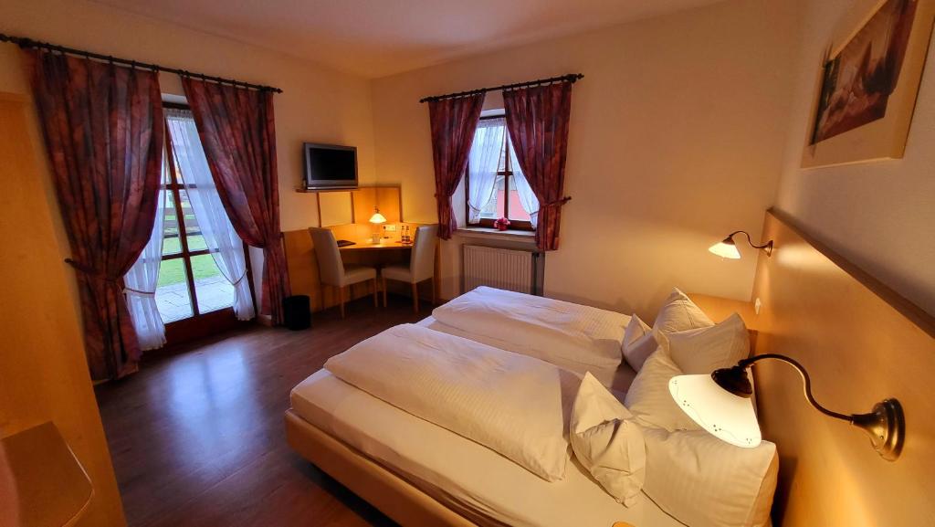 a bedroom with a bed and a desk and windows at La Locanda Ristorante Pizzeria Garni in Ohlstadt