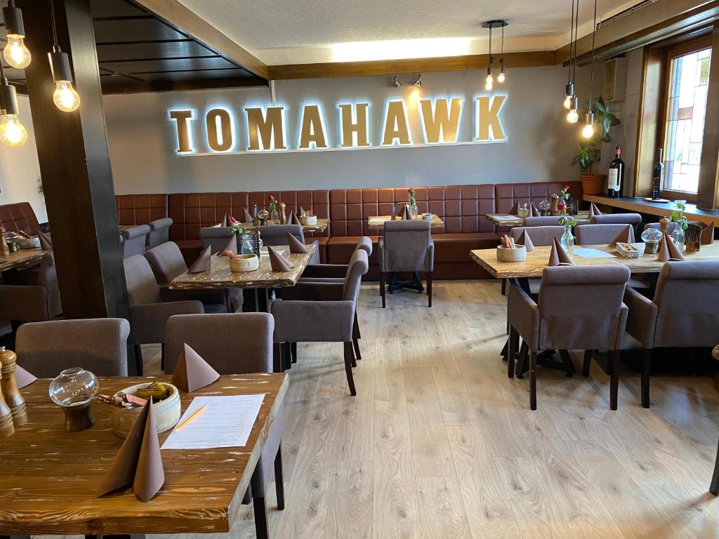 a restaurant with tables and chairs and a sign that reads to miamihawk at Hotel Restaurant Tomahawk in Baiersbronn