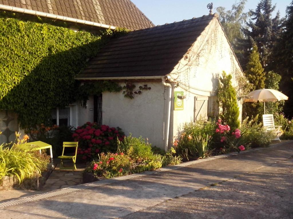 una piccola casa bianca con fiori e un ombrello di Les Nympheas, appart au calme et grand jardin à 15 min de Disneyland, a Crécy-la-Chapelle