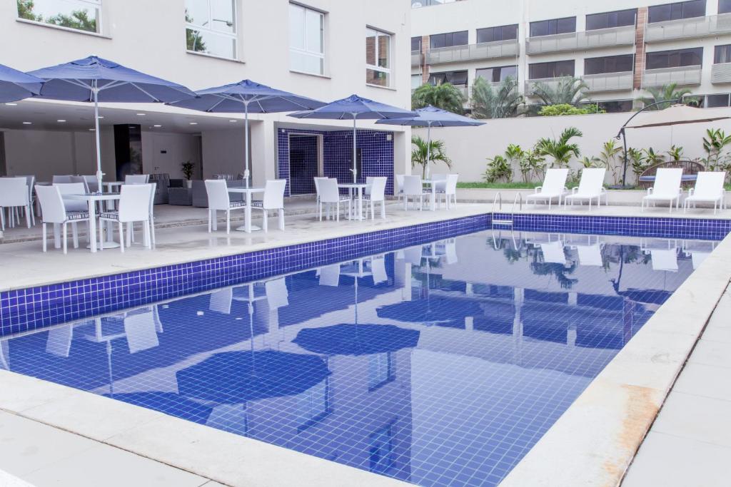 uma piscina com cadeiras e guarda-sóis ao lado de um edifício em Americas Townhouse Hotel no Rio de Janeiro
