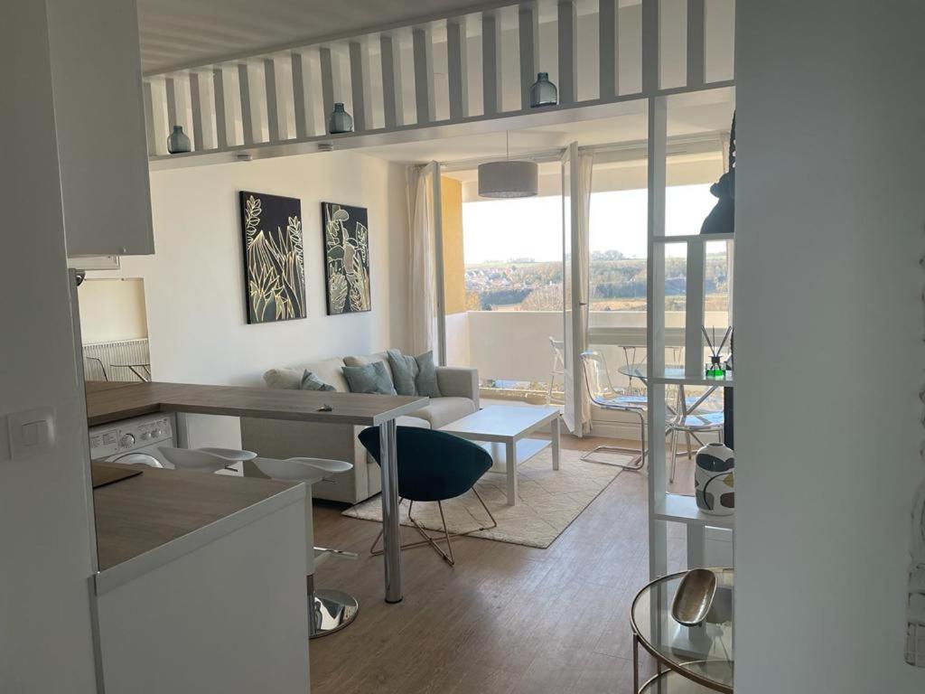 a kitchen and living room with a couch and a table at appartement neuf style architecte au calme in Compiègne