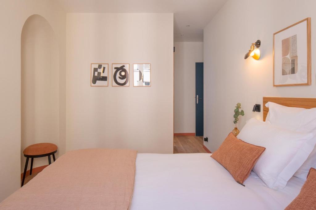 - une chambre avec un lit doté de draps et d'oreillers blancs dans l'établissement Tinah Paris, Aboukir, à Paris