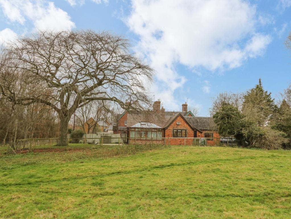 a large house in a field with a tree at 5 Grange Cottages in Southam