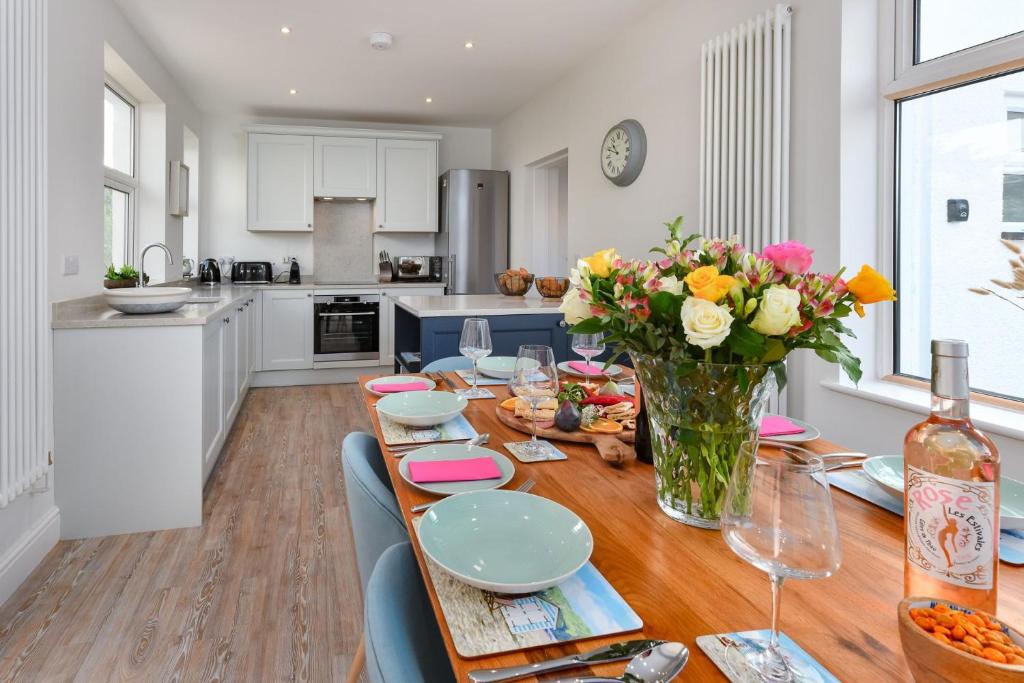 a kitchen with a wooden table with a vase of flowers at Cae Engan in Abersoch