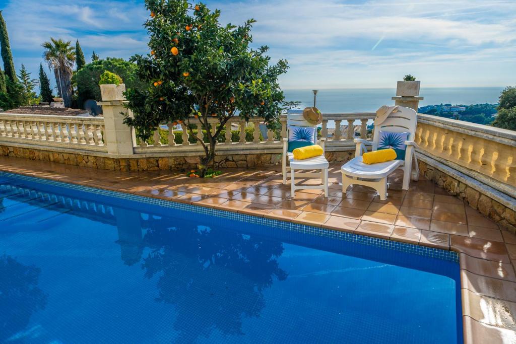 ein Pool mit zwei Stühlen daneben in der Unterkunft Villa Vista Lux, Piscina privada y zona exterior con vista Mar in Tossa de Mar