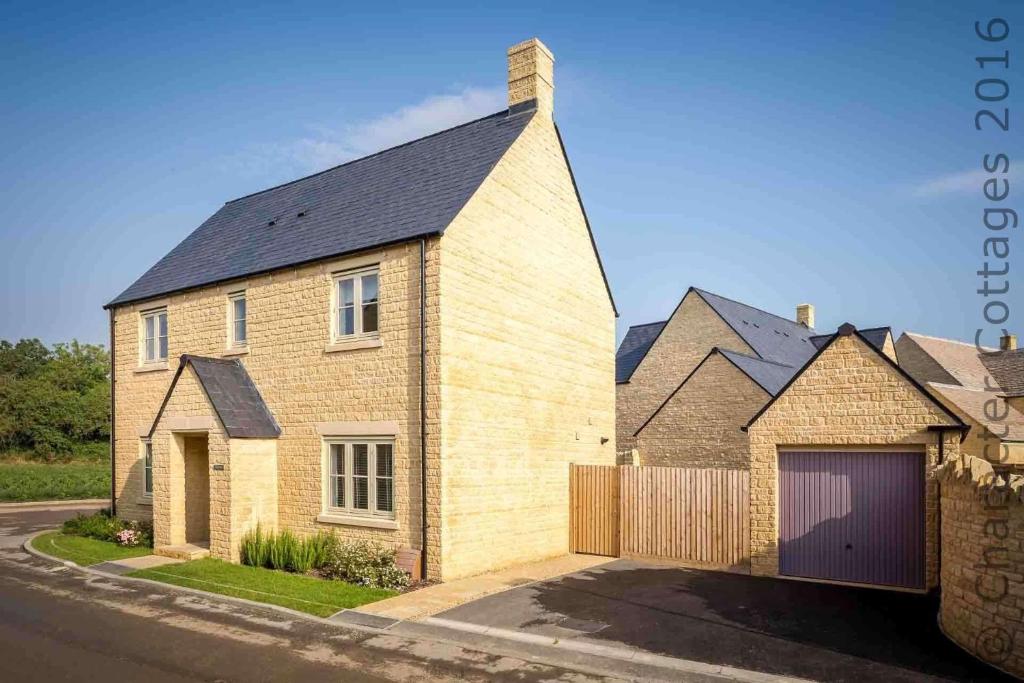 a brick house with a garage on a street at The Bybrook in Bourton on the Water