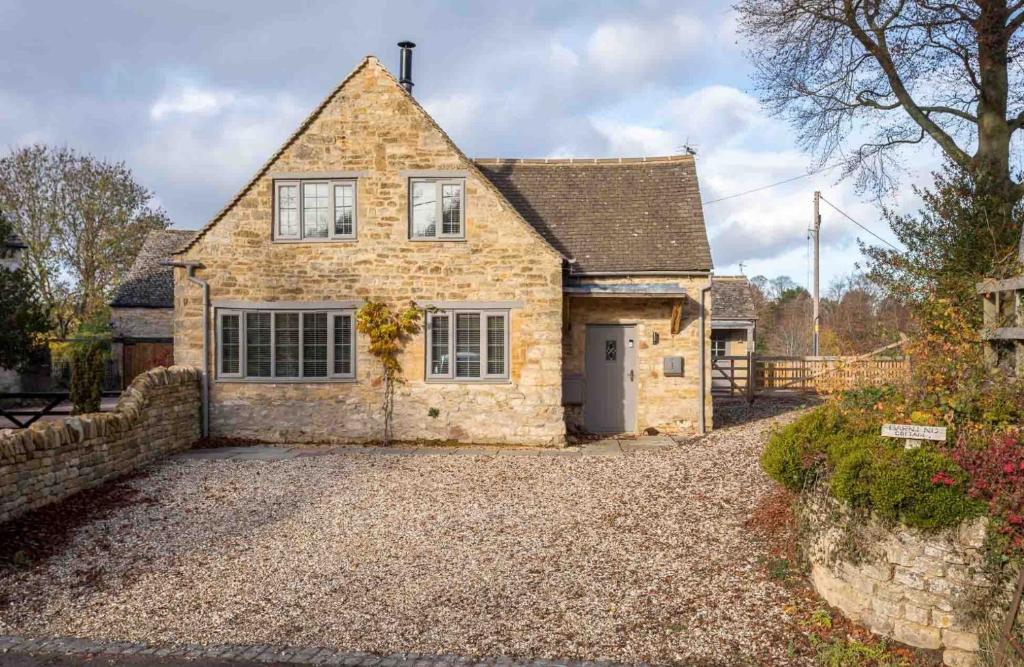 a stone house with a driveway in front of it at Barn End Cottage in Chipping Campden