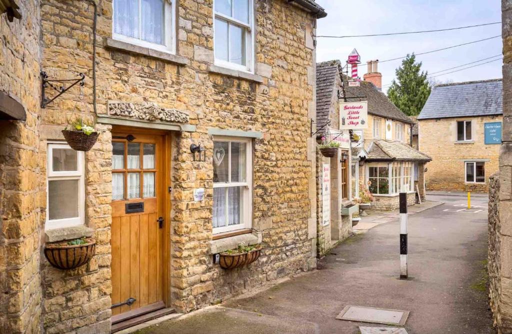 an old stone building with a wooden door on a street at Inglenook Cottage in Bourton on the Water