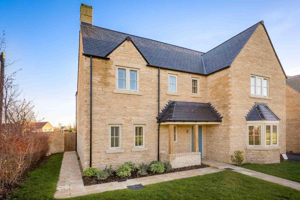 a large brick house with a black roof at Honeystones in Bourton on the Water