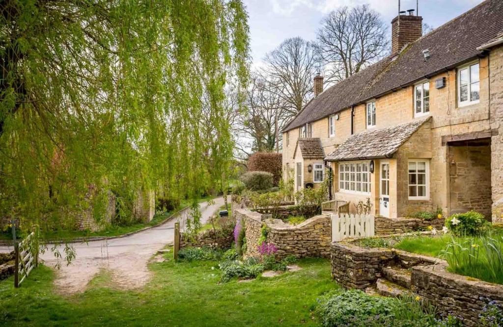 an old stone house with a garden in front of it at Willow Cottage in Hampnett