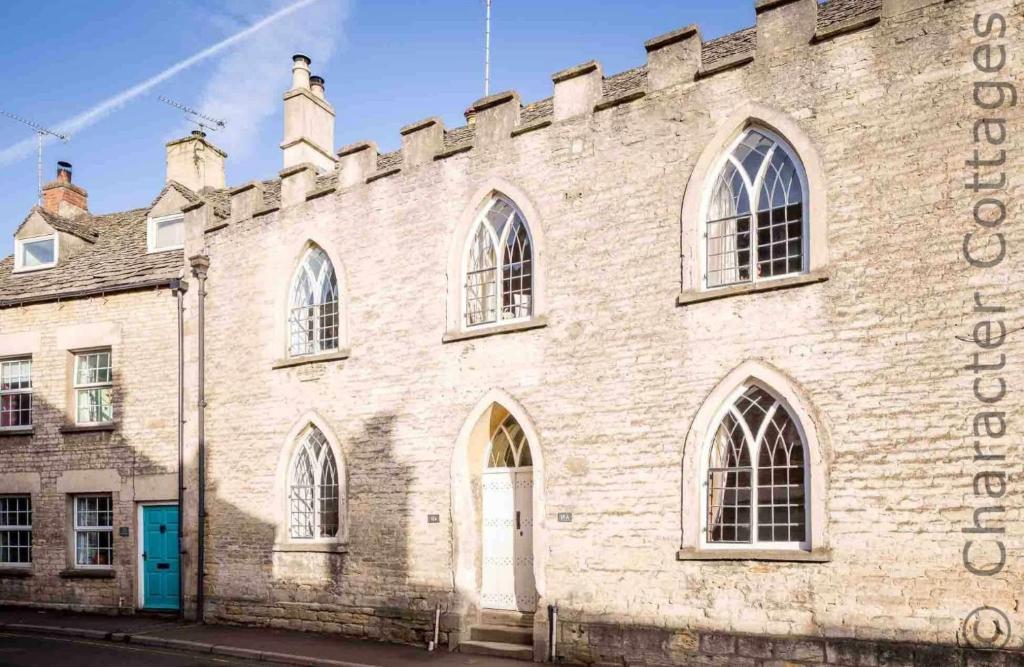 - un grand bâtiment en briques avec des fenêtres et une porte bleue dans l'établissement Little Culver, à Minchinhampton