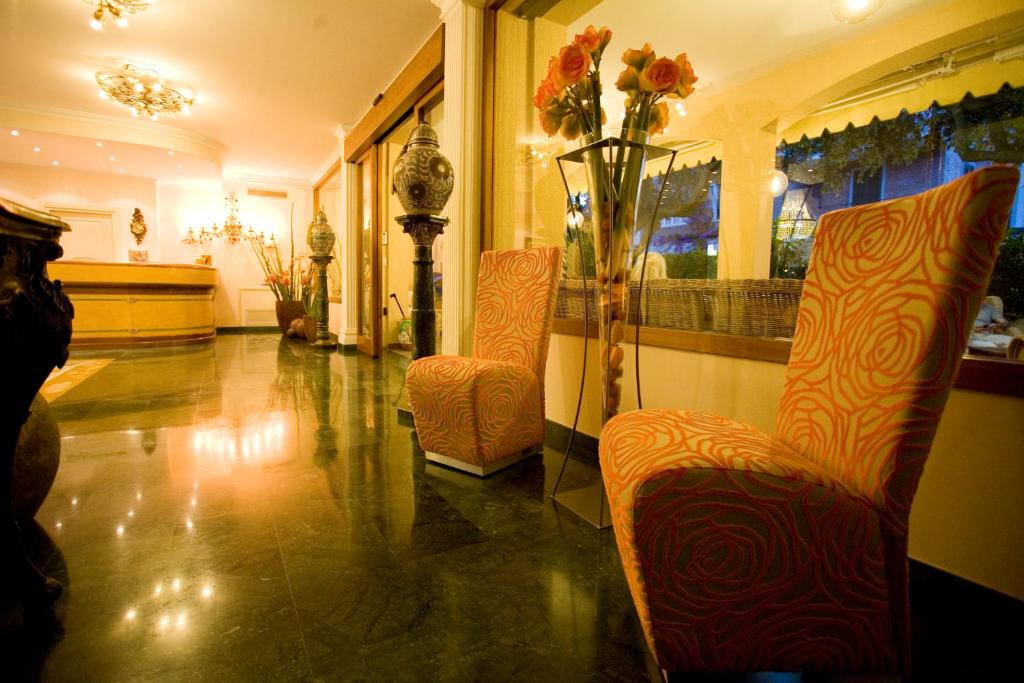 a lobby with two chairs and a vase of flowers at Hotel Atlantico in Castiglioncello