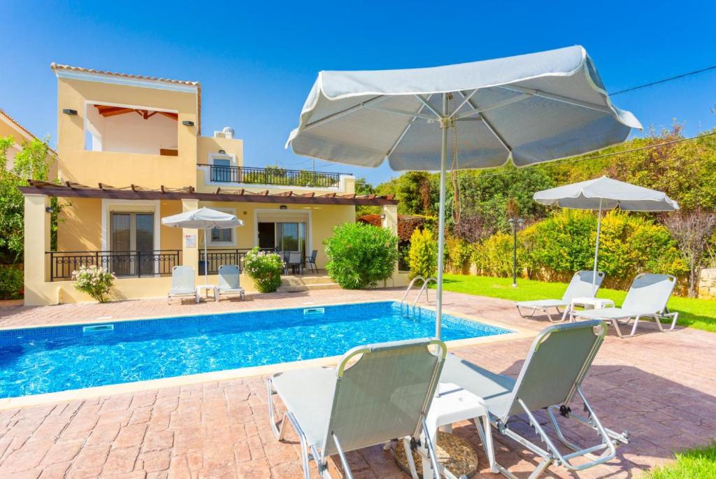 a villa with a swimming pool with chairs and an umbrella at Villa Georgia in Gerani