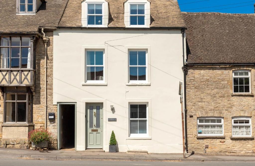 a white house with a green door on a street at Copperbeech in Stow on the Wold