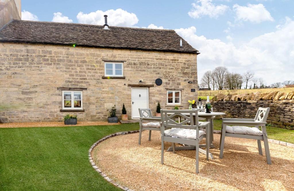 a stone house with a table and chairs in front of it at The Creamery in Nymphsfield