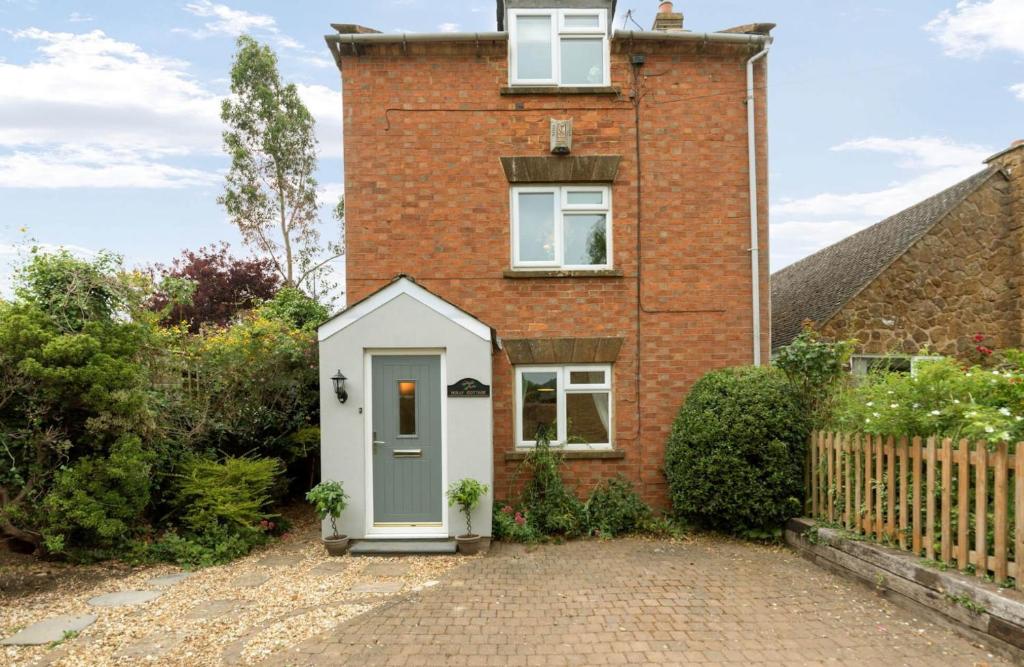 une maison en briques avec une porte blanche devant dans l'établissement Holly Cottage Middle Tysoe, à Middle Tysoe