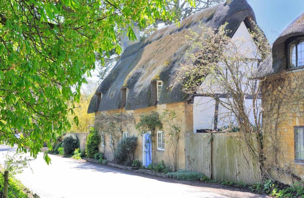 an old stone house with a thatched roof at Pye Corner Cottage in Broadway