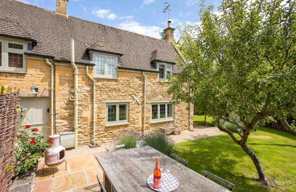 a stone house with a wooden table in front of it at Wyncliffe in Chipping Campden