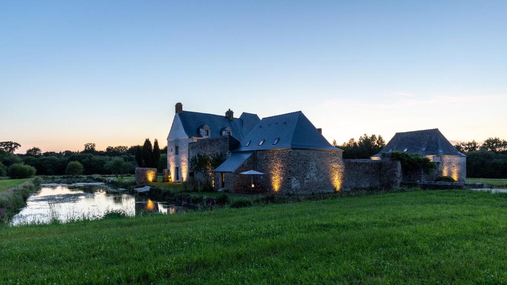 ein Anwesen mit einem Fluss im Vordergrund in der Unterkunft Manoir du Guern in Pluvigner